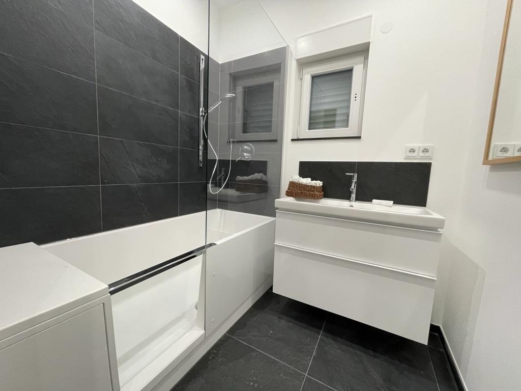 Schwarz-weißes Bad mit Badewanne und Glasabtrennung